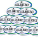A pyramid of ten size 5 Gilbert Barbarian HD match rugby balls, each white with blue and green accents, branded with Gilbert and included in the Gilbert Barbarian HD Match Rugby Ball Ten Pack.