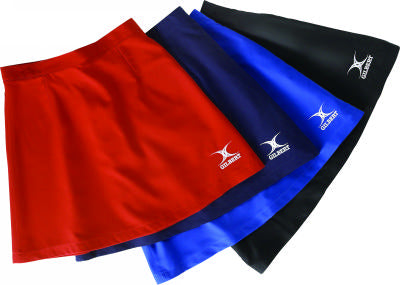 Four athletic skirts in red, navy blue, royal blue, and black are displayed overlapping each other. Each skirt features a white logo on the bottom corner.