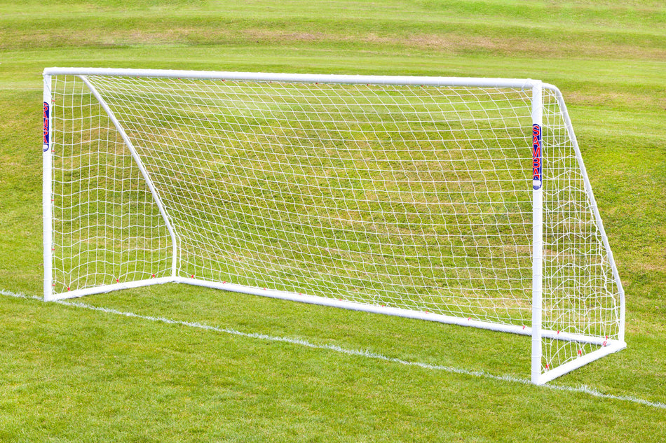 A Samba Sports Samba Match Goal 9V9 16 x 7, crafted from durable uPVC and fitted with its net, stands on a pristine grassy field with green hills in the background.