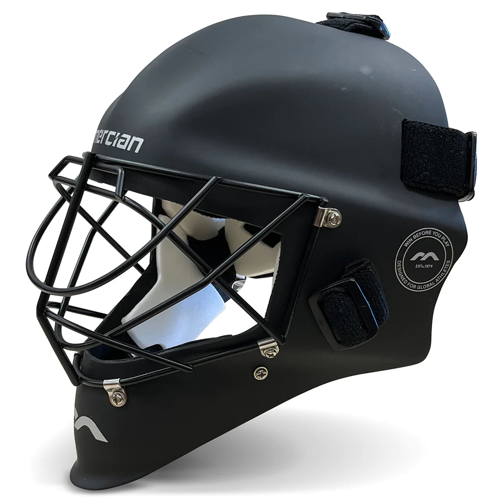 Black field hockey goalie helmet with a metal face cage, adjustable straps, and white interior padding, shown from a side angle on a white background.