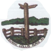 A wooden signpost stands behind a fence with green bushes at its base and trees in the background. A banner below reads NOMINI COLLIS AURIS XI.