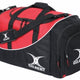 A red and black duffel bag with the word GILBERT and a white logo printed on the side and strap, featuring zippered compartments and a padded shoulder strap.