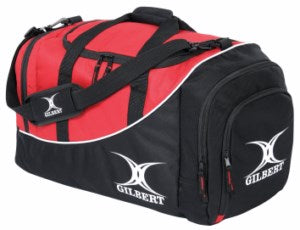 A red and black duffel bag with the word GILBERT and a white logo printed on the side and strap, featuring zippered compartments and a padded shoulder strap.