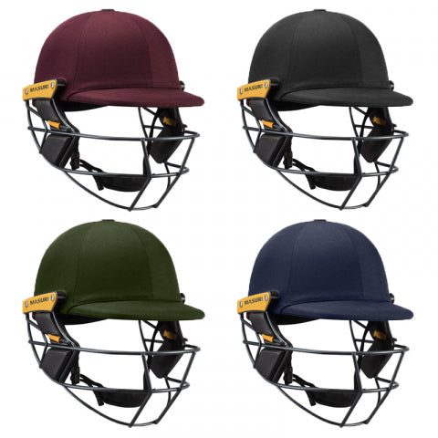 Four cricket helmets in maroon, black, green, and navy blue colors, each with a yellow Masuri branding and protective face grill, arranged in a two-by-two grid on a white background.