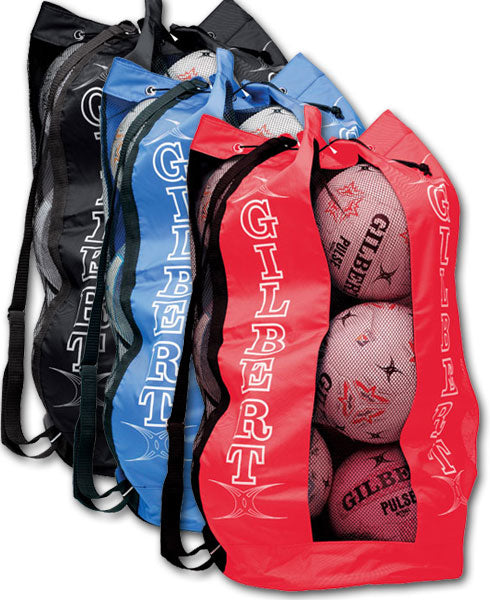 Three mesh sports bags in black, blue, and red, each labeled Gilbert, are filled with rugby balls and standing upright, with shoulder straps visible.