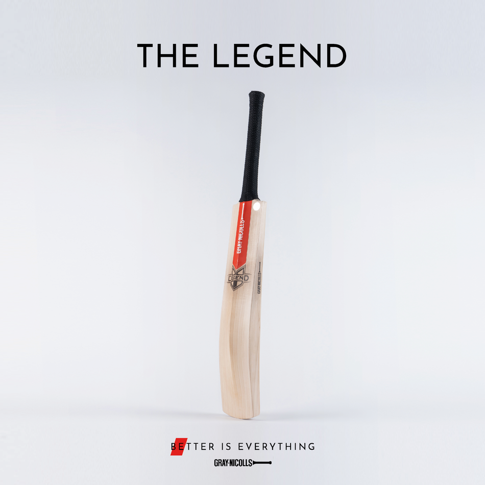 A cricket bat with a red and white Gray-Nicolls label stands upright on a plain background. The text above reads THE LEGEND, and below is the slogan Better is Everything.
