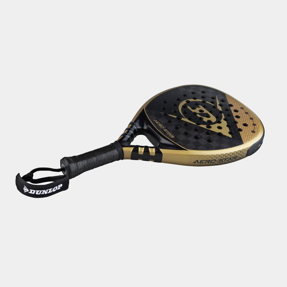 The Dunlop Aerolite Padel Racket, in black and gold, features a Hyper Gryp finish, perforated surface, textured grip, and a DUNLOP-branded wrist strap, displayed on a plain white background.