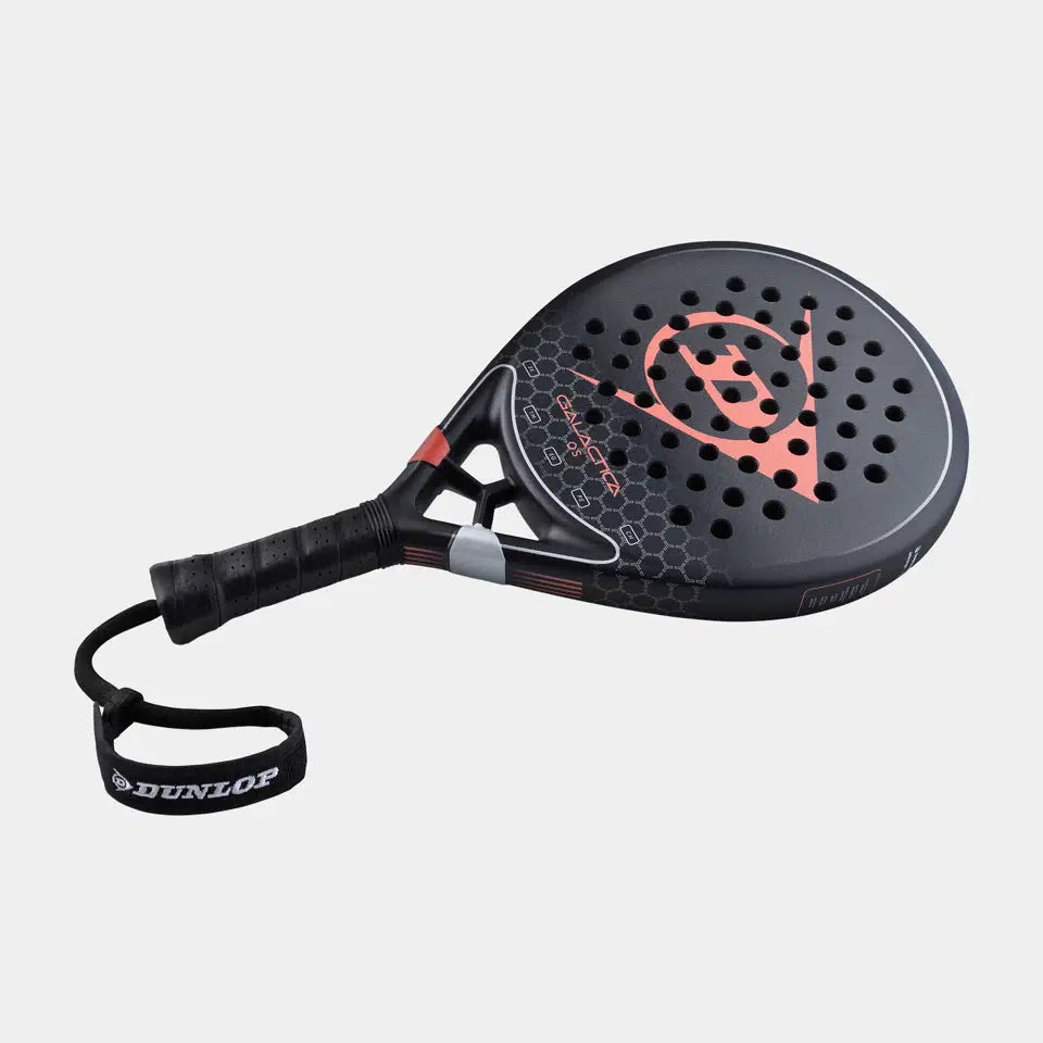 The Dunlop Galactica OS Padel Racket has a black design with red and gray accents, Tri-Max reinforcement, honeycomb pattern, perforated surface, ergonomic grip, and a wrist strap with the Dunlop logo on a plain light background.