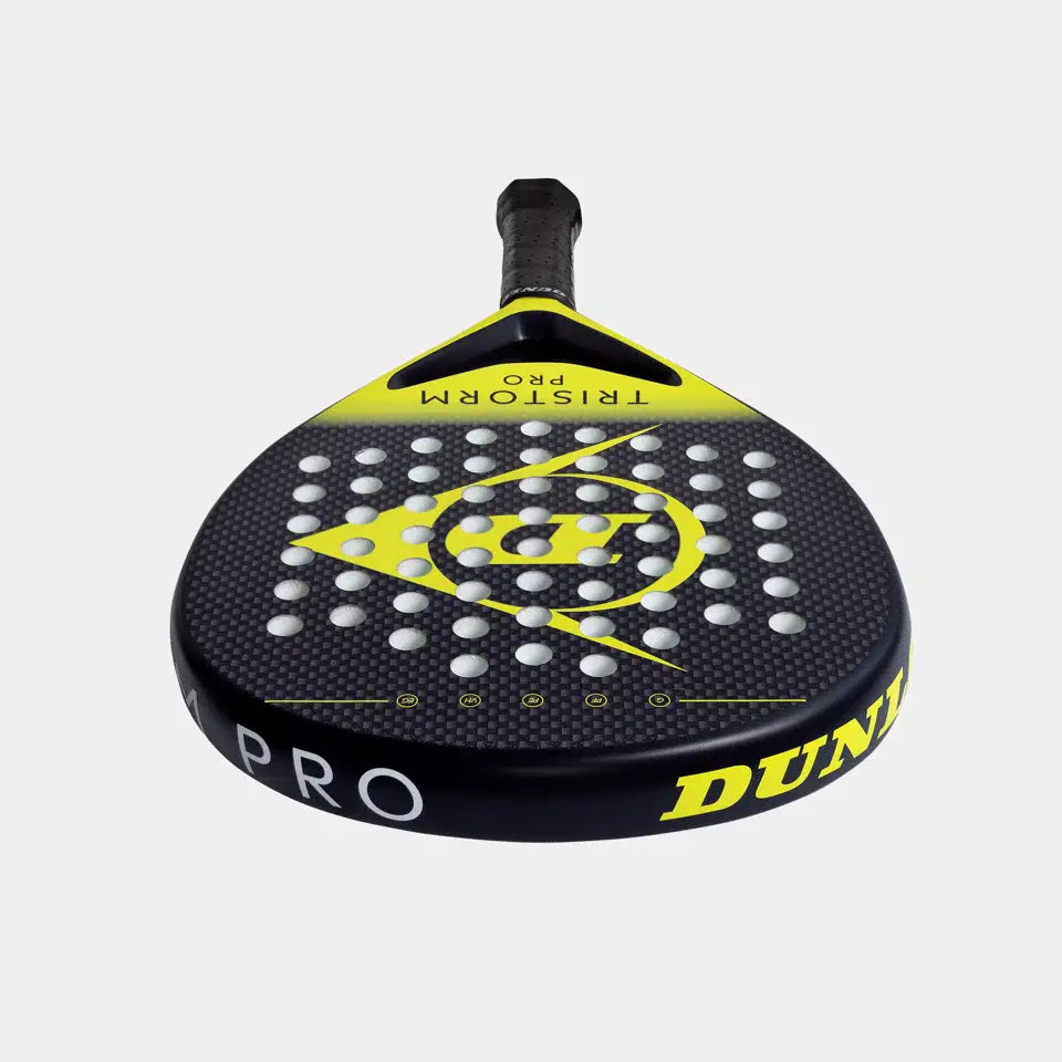 A close-up of the Dunlop Tristorm Pro Padel Racket, showcasing its black and yellow design, multiple round holes on the face, Power Frame technology, and TRISTORM PRO branding on the upper yellow edge.