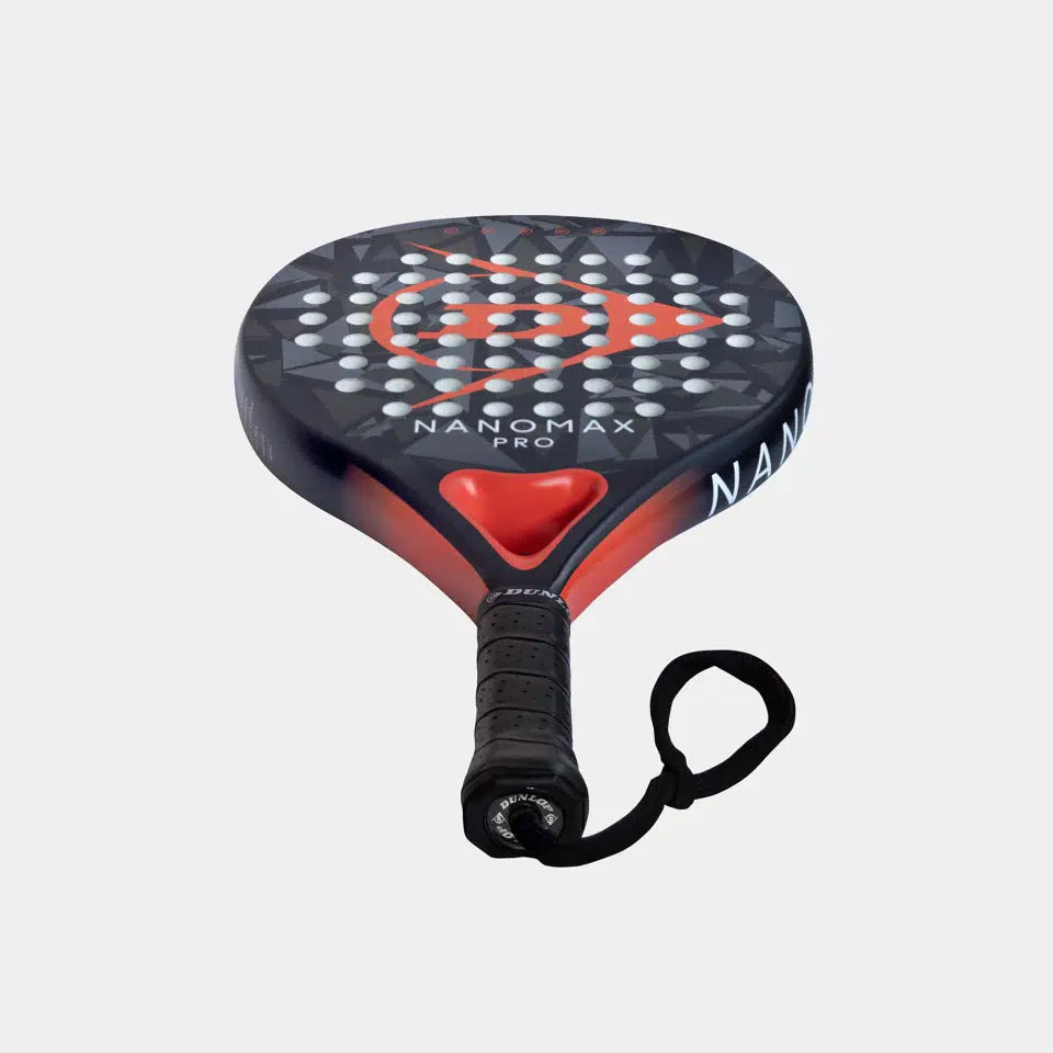The Dunlop Nanomax Pro Padel Racket features a graphite frame, Pro EVA core, wrist strap, and a black/red hybrid head with a geometric pattern of white holes.