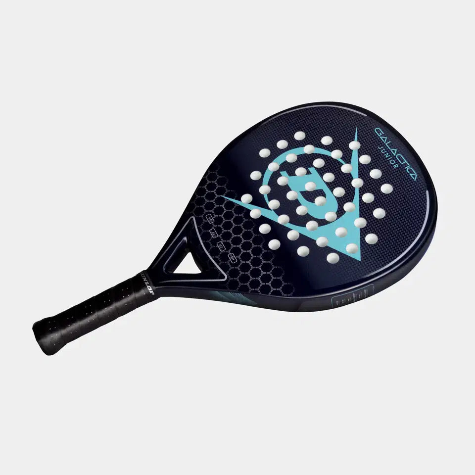 The Dunlop Galatica Junior Padel Racket features a black and blue design with a light blue Dunlop logo, honeycomb pattern, white circular holes, graphite frame, and textured black grip handle. The background is plain white.