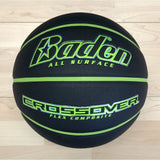 A black Baden Sports Crossover Basket Ball with green accents and a flex composite cover, displaying the phrases “ALL SURFACE” and “CROSSOVER FLEX COMPOSITE,” rests on a light wooden floor—making it an ideal indoor-outdoor basketball.