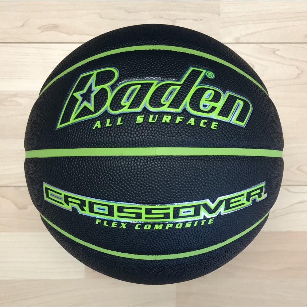 A black Baden Sports Crossover Basket Ball with green accents and a flex composite cover, displaying the phrases “ALL SURFACE” and “CROSSOVER FLEX COMPOSITE,” rests on a light wooden floor—making it an ideal indoor-outdoor basketball.