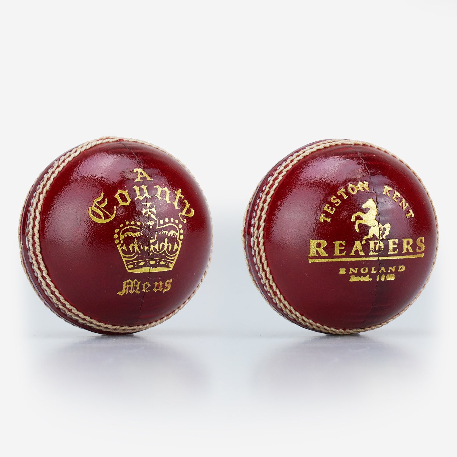 Two red, hand-stitched cricket balls by Readers: one is the County Crown Cricket Ball with "A County Meus" and a crown; the other says "Teston Kent Readers England Estd. 1808" with a horse emblem. Both made from premium English leather.