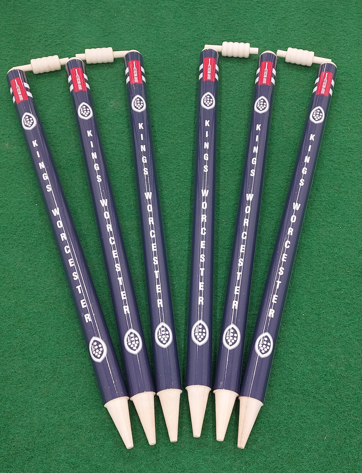 Six novelty pencils with Gray Nicolls’ Custom Printed Club Cricket Stumps design, each topped with a tiny abacus, are arranged fan-like on green—ideal for cricket fans or anyone wanting standout desk accessories.