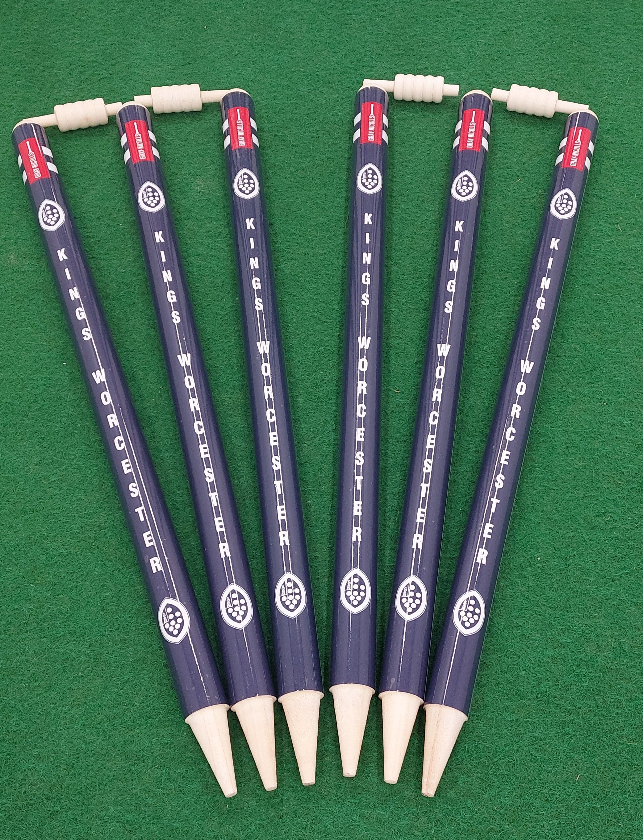 Six novelty pencils with Gray Nicolls’ Custom Printed Club Cricket Stumps design, each topped with a tiny abacus, are arranged fan-like on green—ideal for cricket fans or anyone wanting standout desk accessories.