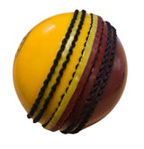 A close-up of the Hunts County Bomber Ball by Hunts County, showing one half red and the other yellow with prominent black stitched seams, isolated on a white background.