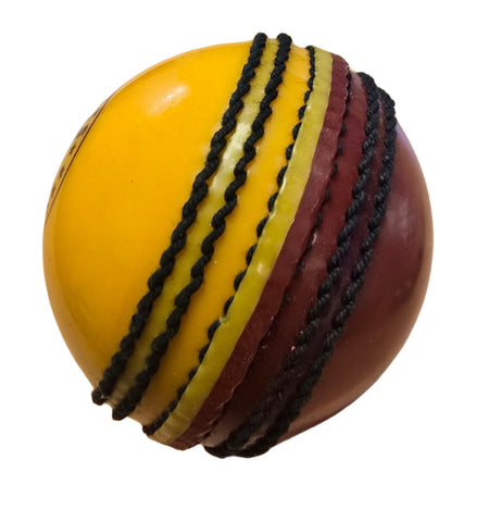 A close-up of the Hunts County Bomber Ball by Hunts County, showing one half red and the other yellow with prominent black stitched seams, isolated on a white background.