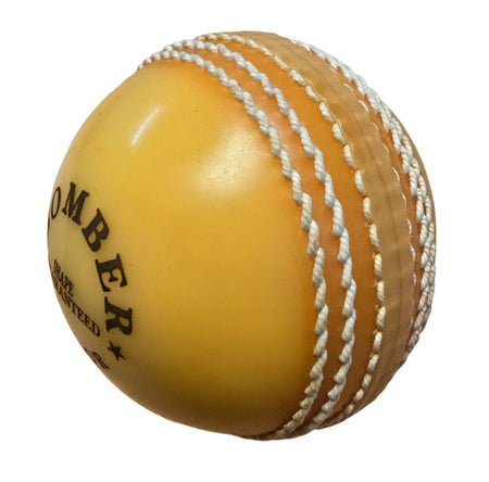 A close-up of the yellow Hunts County Bomber Ball by Hunts County, featuring white stitched seams and partial black text, displayed on a plain white background—perfect for cricket training or power practice sessions.
