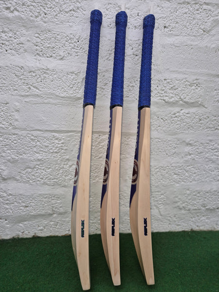 Three Hunts County Reflex Senior Cricket Bats with blue handles stand upright on green turf against a white brick wall—a top pick for senior players by Hunts County.
