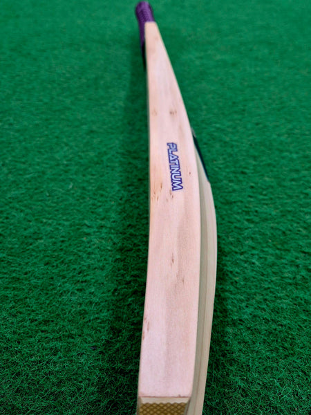 A close-up of a Hunts County Platinum Players Senior Cricket Bat, crafted from premium English Willow, lying on a green textured surface, highlighting the elegant curve from the handle to the toe.