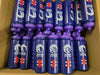 A cardboard box holds Martin Berrill Sports’ Customised Branded Water Bottles, featuring your club or school logo—blue bottles with purple lids, red, white, and blue side designs.