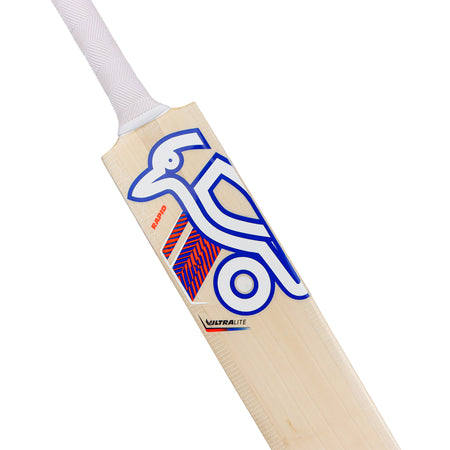 A close-up of the lightweight Kookaburra Rapid Ultralite Cricket Bat 2026, featuring a white handle and blue geometric bird design on its English Willow blade, branded with RAPID and ULTRALITE.