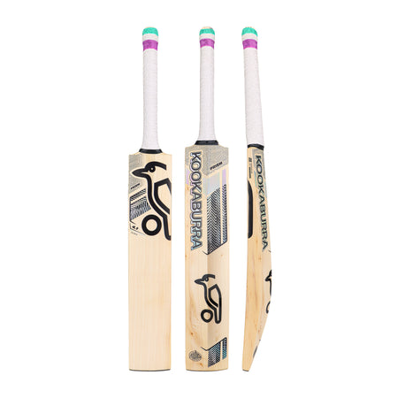 Three Kookaburra Prism 4.1 Hero Cricket Bat 2026 models stand upright, displaying front, side, and back views. Each bat has white handles with green, purple, and pink grip accents, black branding on light wood, and balanced performance.
