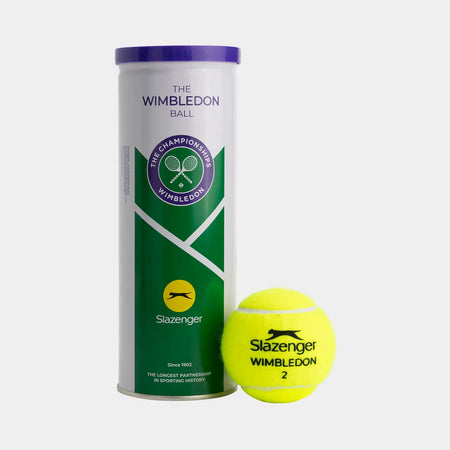 A Slazenger Wimbledon 3 Ball Tin stands upright next to a yellow official ball marked "Slazenger Wimbledon 2." The tin features Wimbledon branding in white, green, and purple.