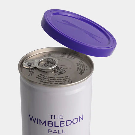 A partially opened Slazenger Wimbledon 4 Ball Tin with a purple lid on top, containing official championship grass court tennis balls. Set includes six dozen balls (18 tins). Shown against a plain white background.