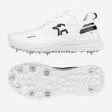 The Kookaburra KC Players Cricket Spikes are white shoes with black accents, a side logo, and a honeycomb-patterned sole featuring prominent metal spikes for grip. Shown from the side and bottom.