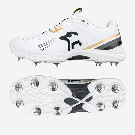 The Kookaburra KC 3.0 Cricket Spikes 2026 by Kookaburra feature a white design with gold and black accents, metal spikes, and a kangaroo logo. Ideal for club players, one shoe is shown from the side and another displays the spike layout.
