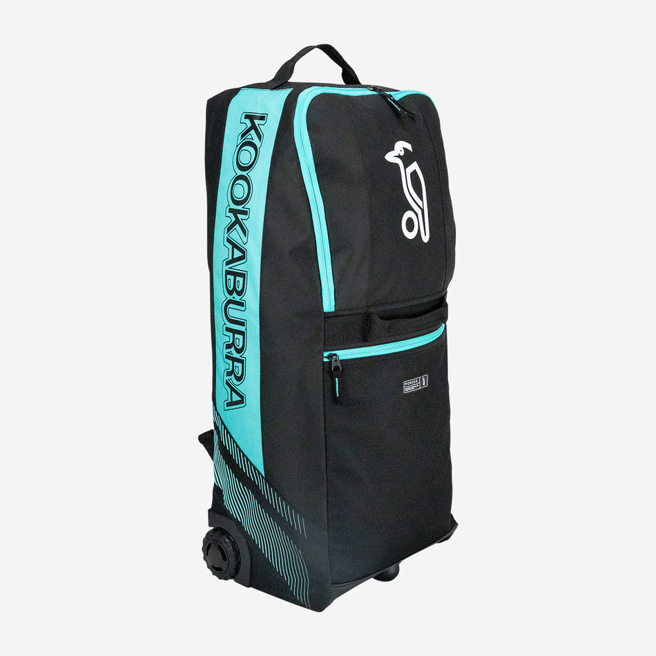The Kookaburra WD6000 Junior Wheelie Duffle Bag 2026 in black/teal features wheels, a top handle, zippered compartments, side KOOKABURRA branding, and a white bird logo—ideal for young cricketers.