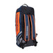 The Kookaburra WD6000 Junior Wheelie Duffle Bag 2026, in navy blue and orange with bold branding and striped details, stands upright on a white background. The bag features wheels and a handle for easy transport.