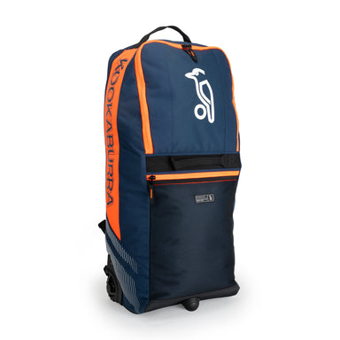 The Kookaburra WD6000 Junior Wheelie Duffle Bag 2026 in navy/orange features a large white brand logo, front pocket, black zippers, and "Kookaburra" in orange—ideal as a junior cricket bag.