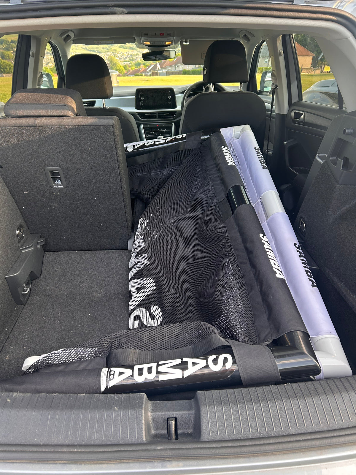 A Samba Sports 4ft x 2.5ft Folding 3v3 Goal is stored in the back of an SUV, with the rear seats partially folded. The car is parked outdoors on a sunny day.