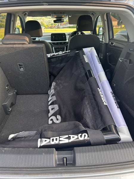 A Samba Sports 4ft x 2.5ft Folding 3v3 Goal is stored in the back of an SUV, with the rear seats partially folded. The car is parked outdoors on a sunny day.