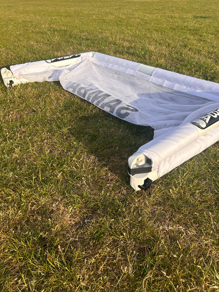 A Samba Sports 4ft x 2.5ft Folding 3v3 Goal lies flat and collapsed on the grassy field under sunlight.