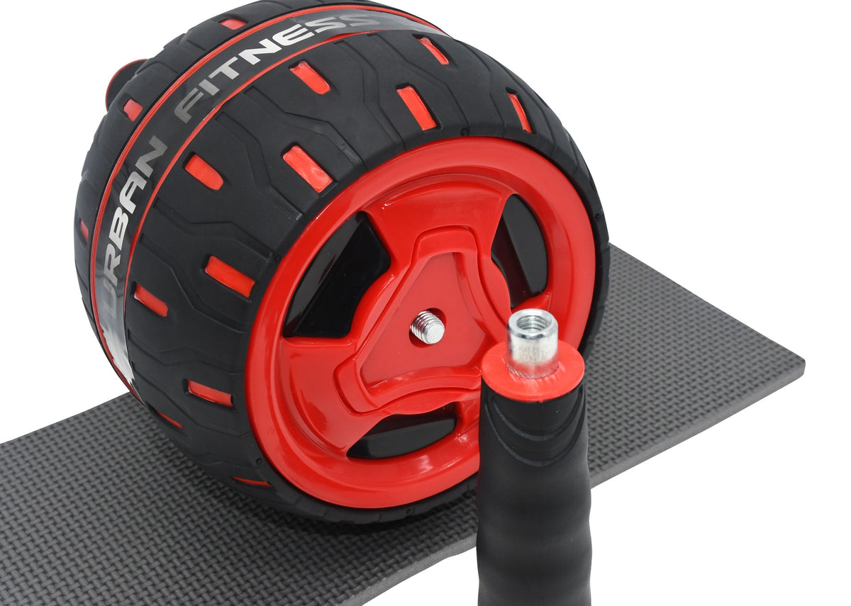 A close-up of the Urban Fitness Rebound Ab Wheel in black and red with branding, on a textured mat; a detachable handle lies in front, making it ideal for building core strength.