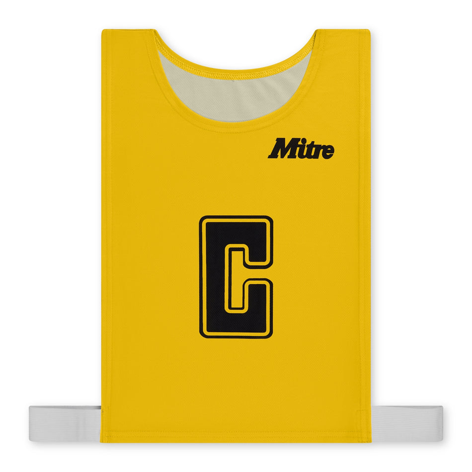 The Mitre Pro Netball Bib set features yellow bibs made from durable polyester micro mesh with a large black "C" outlined in yellow at the center, the "Mitre" brand name in black at the top right, and white elastic straps at the bottom.