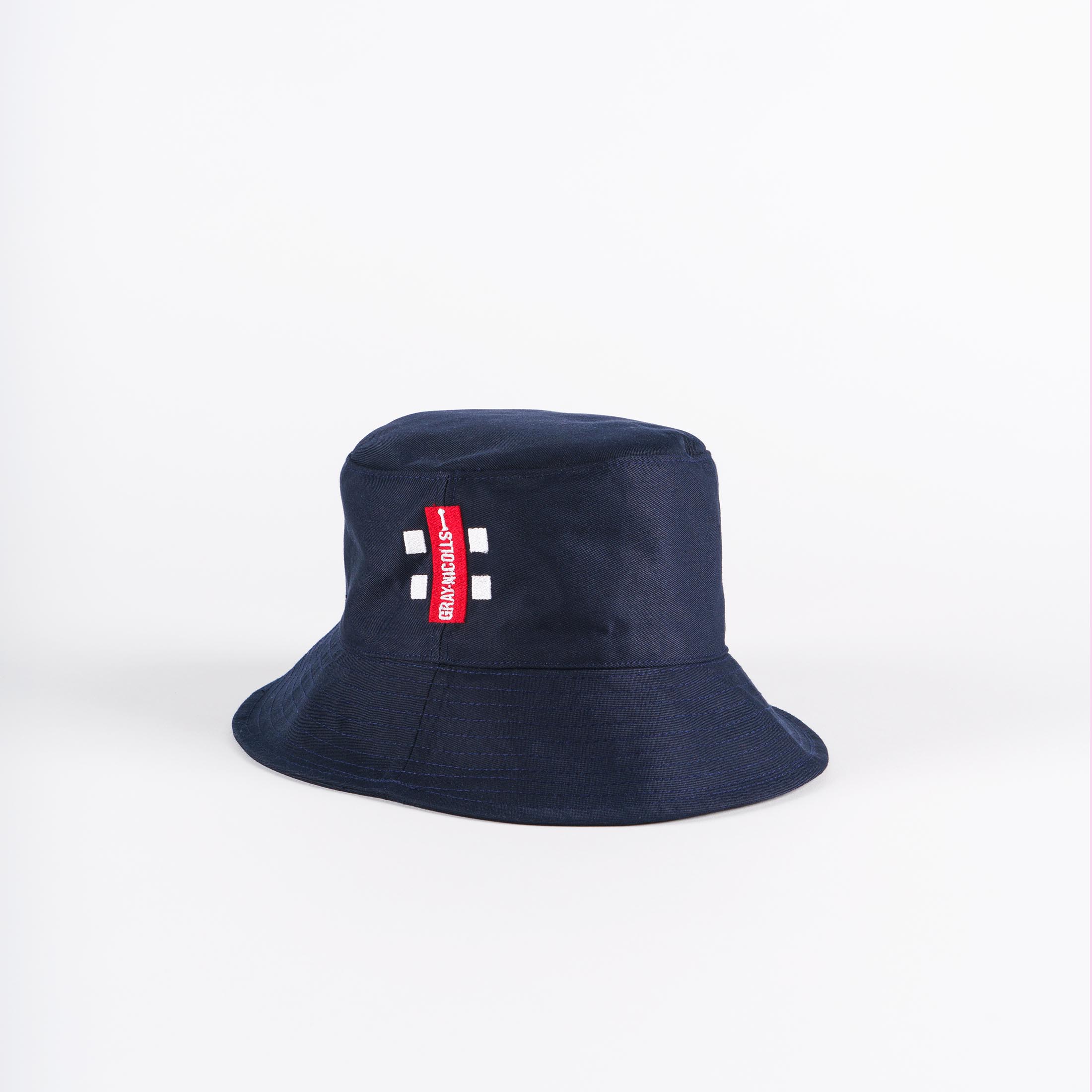 The Gray Nicolls Bucket Hat by Gray Nicolls features a navy design with a red tag and white text on the front, shown against a plain white background.