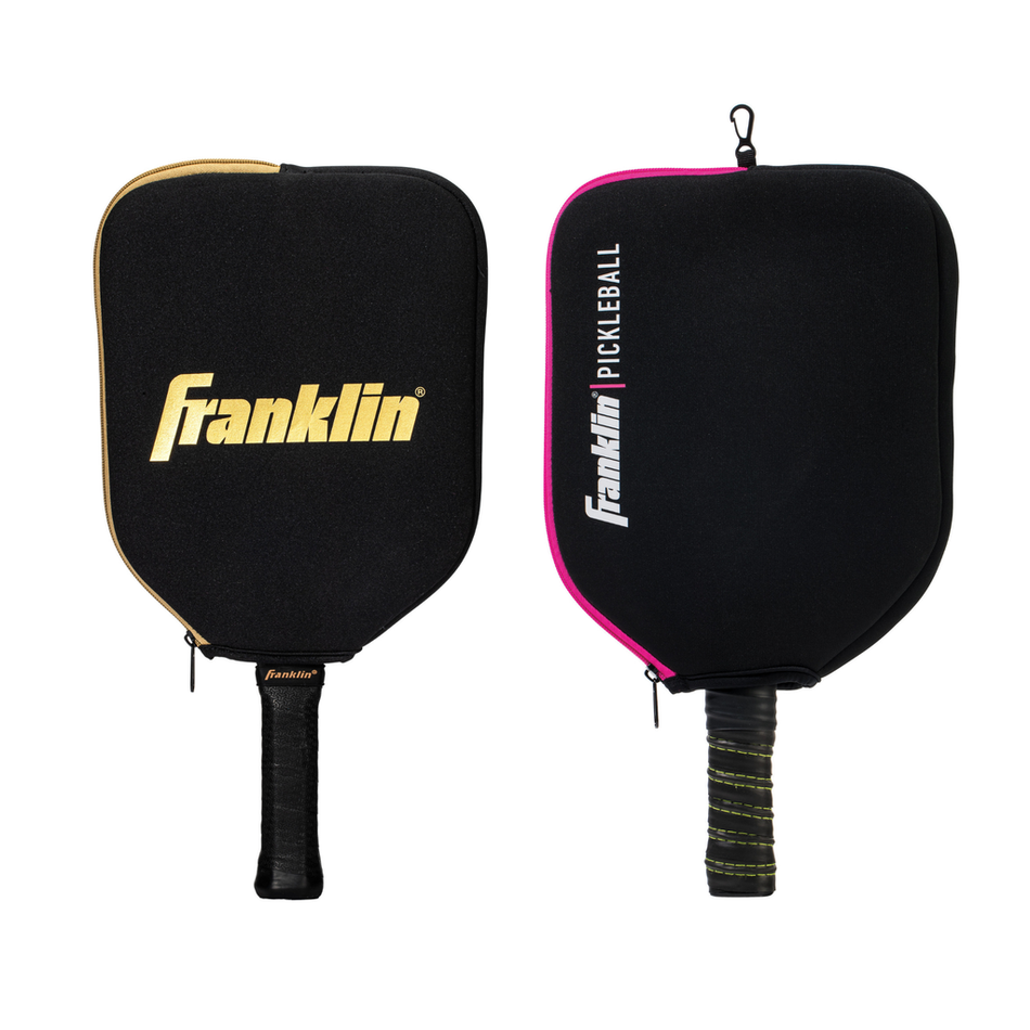 Two Franklin Single Pickleball Paddle Covers by Franklin in Black/Pink, each with built-in fence clips for easy courtside storage. One case features gold trim and logo, the other pink trim with “PICKLEBALL” text. Both handles have black grip tape.