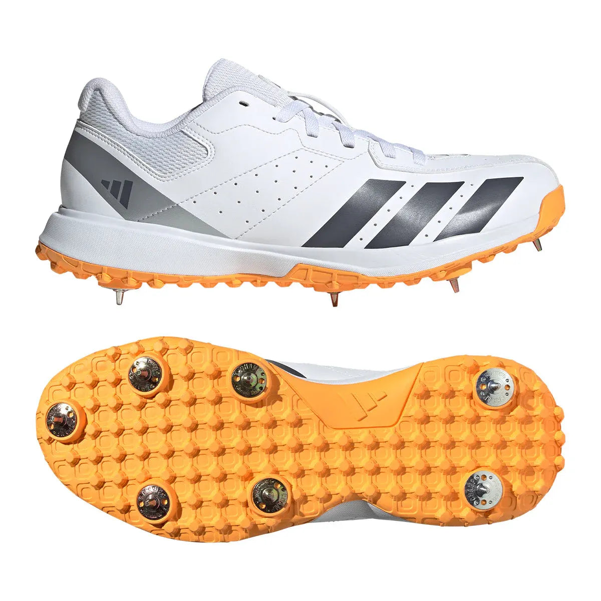 The Adidas Howzat White/Orange Cricket Spikes 2026 are white cricket shoes with gray and black accents, orange soles, and metal spikes. One shoe is shown from the side and the other from below to highlight the spiked sole.