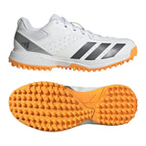 The Adidas Howzat Spikeless Cricket Shoe 2026 features white synthetic leather, orange rubber soles for grip, and black side stripes; one shoe displays a side view while the other highlights its textured sole.