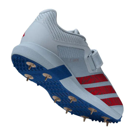 The Adidas 22YDS Vector White/Red/Royal Cricket Spikes 2026 features a light gray upper, red stripes, a lace strap, and a blue sole with metal spikes—ideal for pace bowlers—shown against a white background.