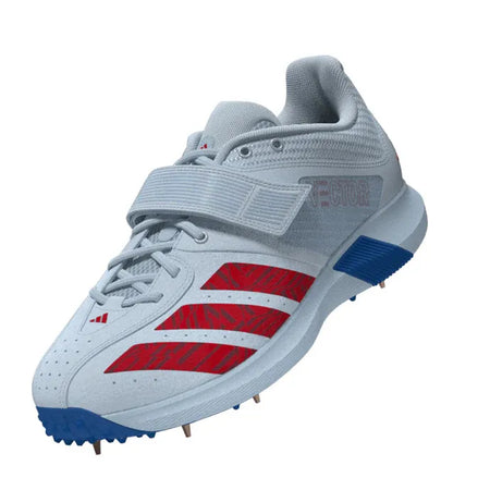 The Adidas 22YDS Vector Cricket Spikes 2026 feature a light gray upper with red stripes, blue accents, and a velcro strap—perfect for pace bowlers seeking both cricket boot support and running spike performance. Color: Crystal Sky/Pure Ruby/Bright Royal.