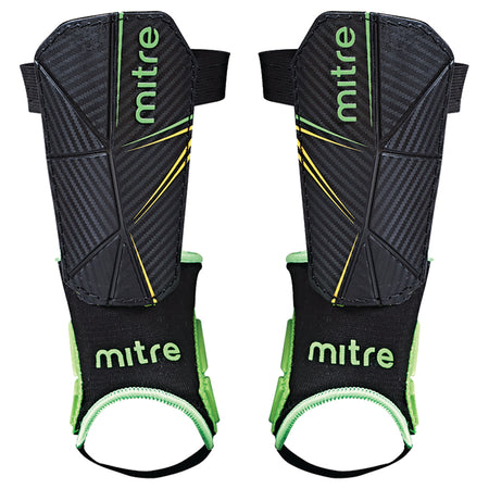 The Mitre Delta Ankle Shinguard features a black design with green and yellow accents, a textured surface, and black ankle supports with green trim for added protection; available in kids’ and men's sizes.
