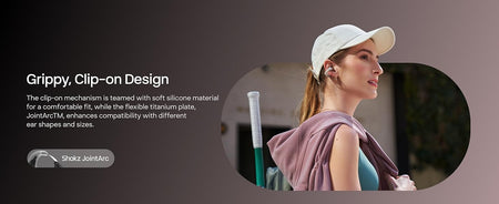 A woman in a white cap and pink top wears Shokz OpenDots One open-ear, clip-on earbuds by Shokz, featuring a grippy soft silicone fit, flexible titanium plate for comfort, and immersive audio designed for all-day wear.