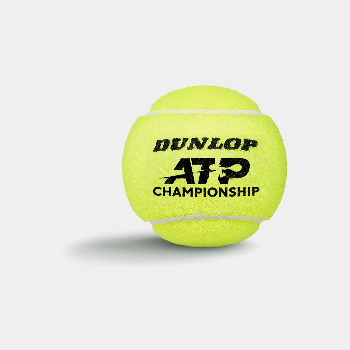 A bright yellow Dunlop ATP Championship Tennis Ball from the 3 Ball Tube, with a white seam and black logo, lies on a light gray background casting a soft left shadow.