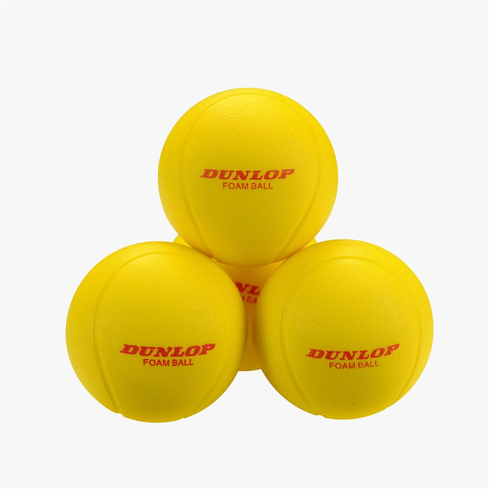 A set of Dunlop Training Foam Tennis Balls (12 Pack) is shown stacked on a white background, ideal for introducing kids to tennis. The bright yellow balls feature "DUNLOP FOAM BALL" printed in red.